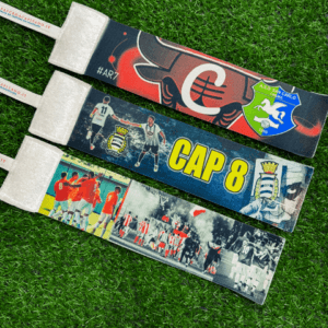 3 fasce da capitano distese sull'erba del campo da calcio